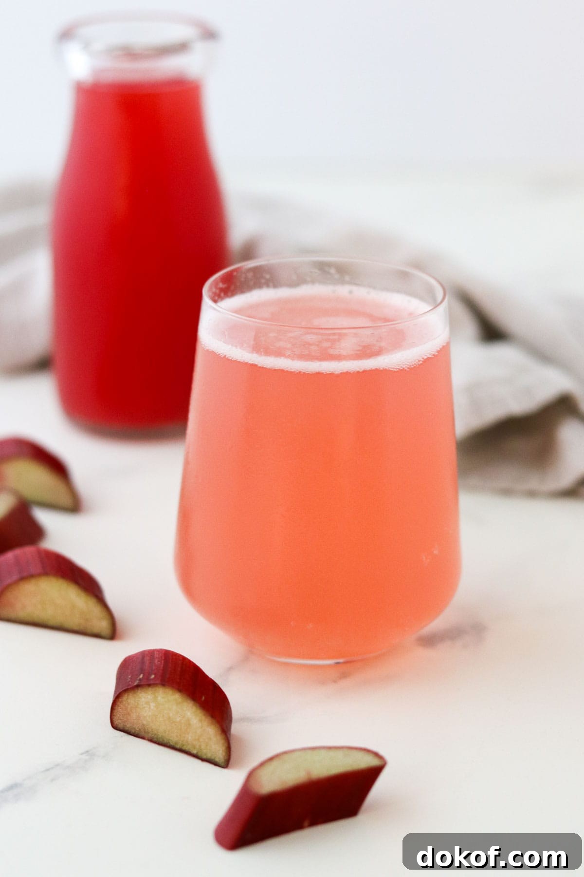 sparkling water with rhubarb syrup in a glass next to cut up rhubarb.