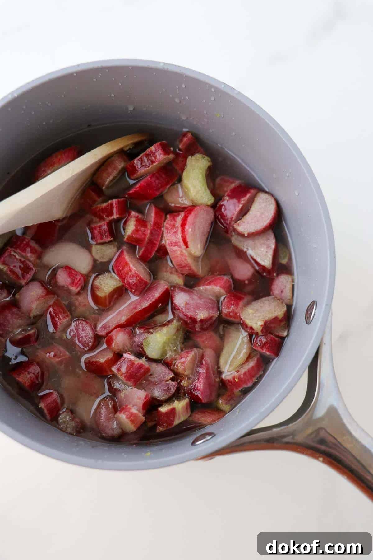 Cut up rhubarb in a saucepan with a wooden spoon.