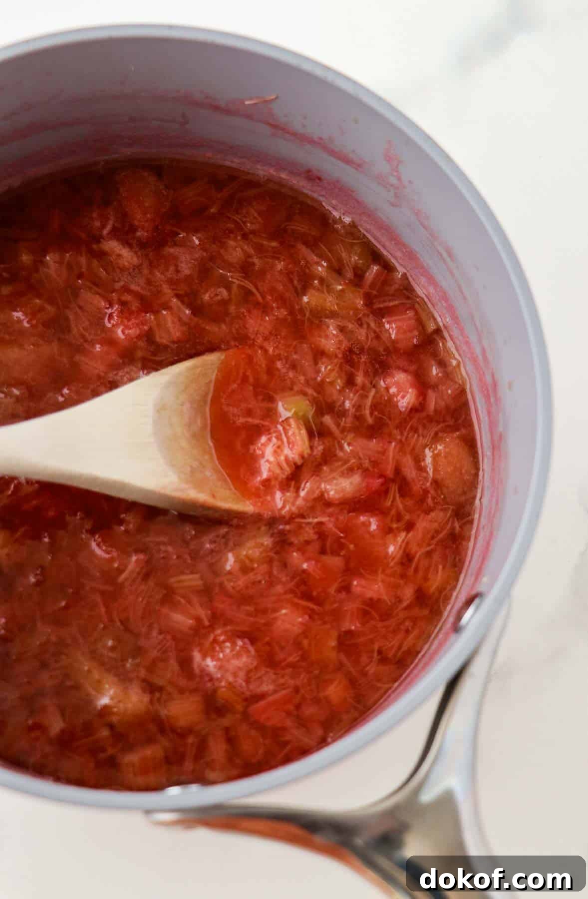 Cooked rhubarb in a saucepan with a wooden spoon.