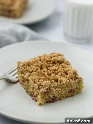Old-Fashioned Norwegian Rhubarb Crumb Cake on a plate next to a glass of milk.