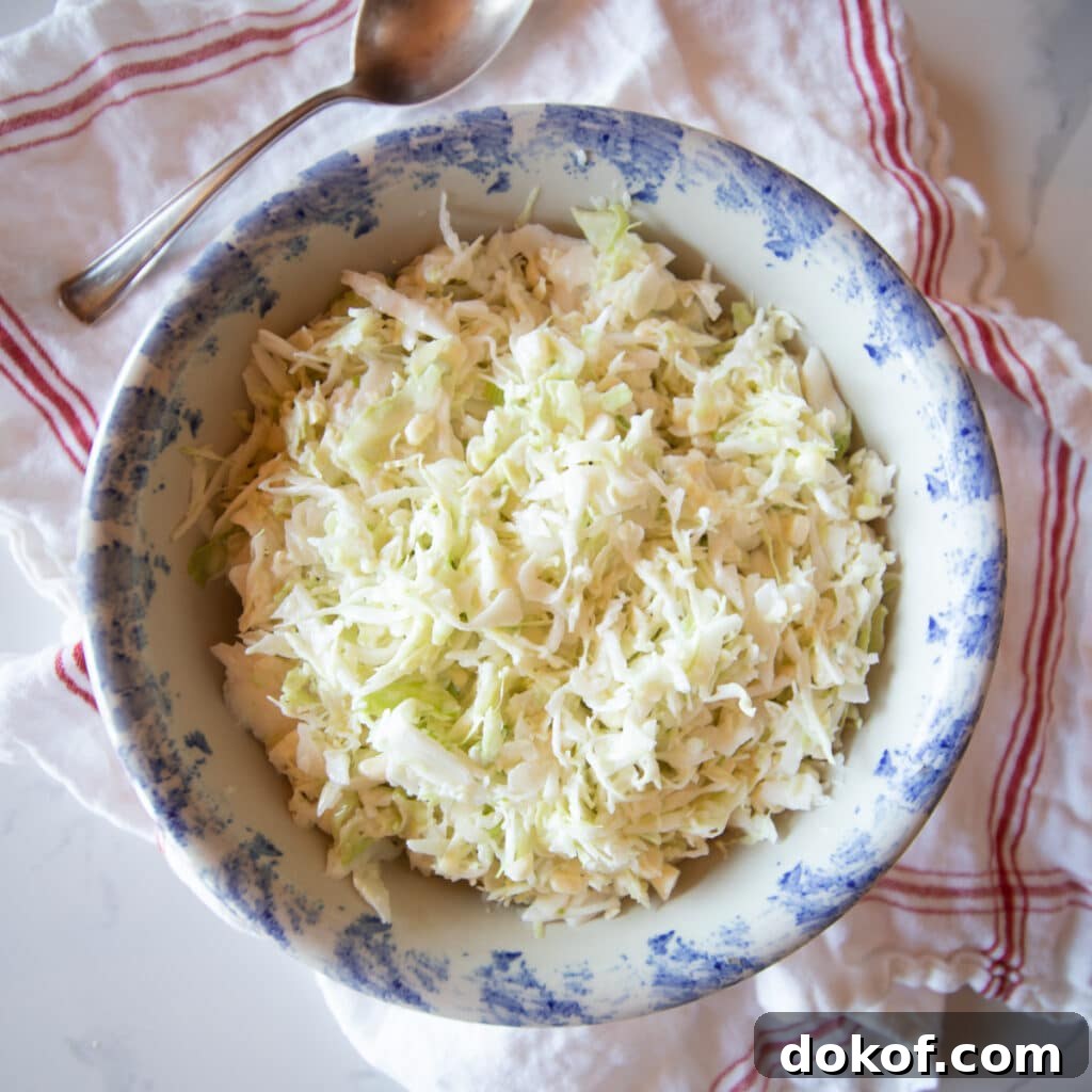 A blue and white bowl filled with buttermilk coleslaw with a serving spoon.