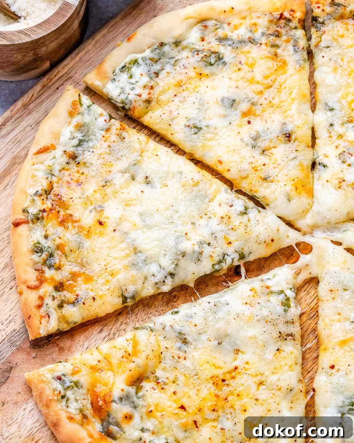 High-Protein White Pizza Recipe for Muscle Building 8 A close up of white pizza sliced into wedges on a wooden board.