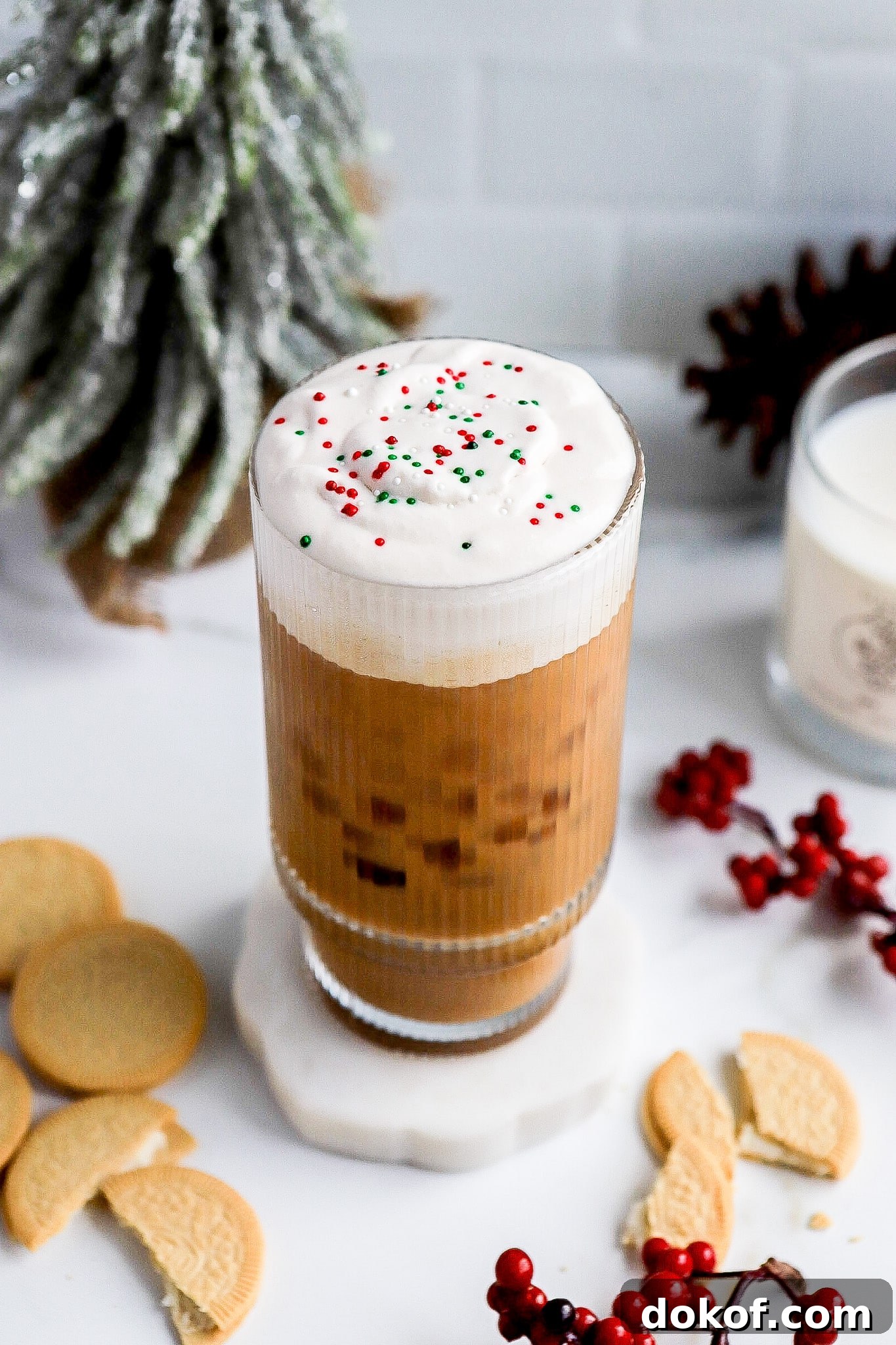 Starbucks-Style Sugar Cookie Cold Foam Recipe — Copycat Guide 6 Side angle of holiday Starbucks drink with red and green sprinkles and vanilla cookies in foreground.