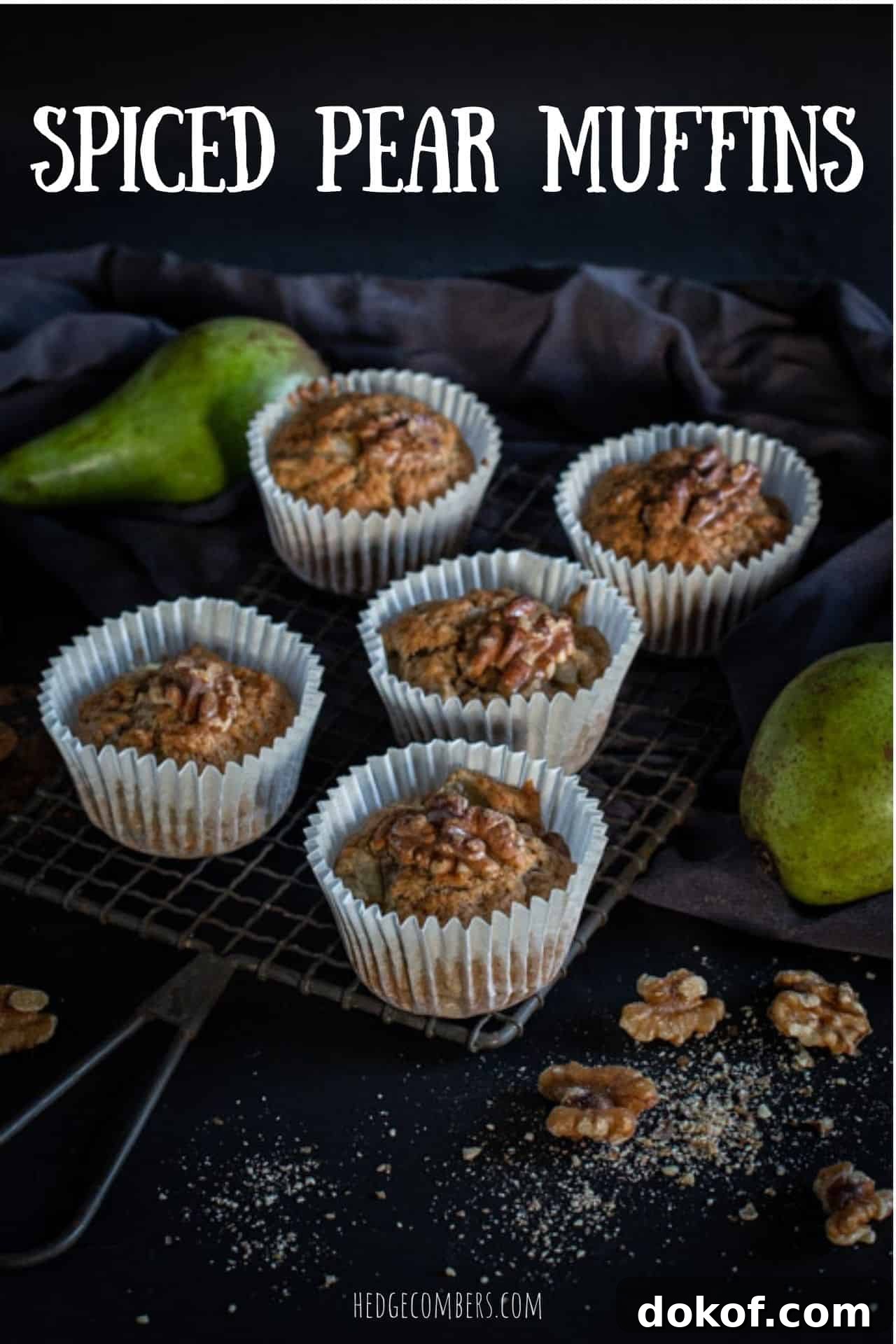 black background and 5 pear muffins on a rustic cooling rack with raw green pears and walnut halves scattered around