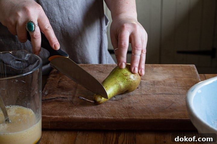 womans hands cutting up a green pear on a wooden chopping board