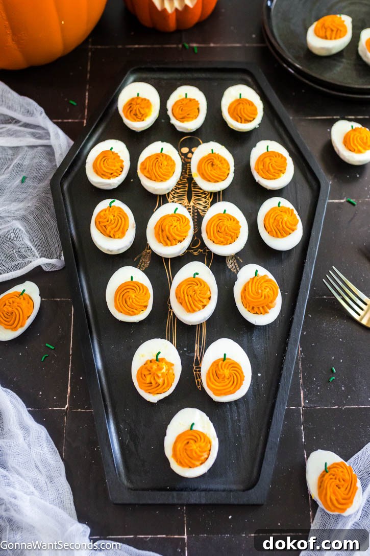 These spooky-cute Halloween Deviled Eggs have black-cracked shells and creamy orange filling. It's a stunning addition to any Halloween spread! #halloweenappetizers #deviledeggs Halloween Deviled Eggs on a coffin shaped serving tray