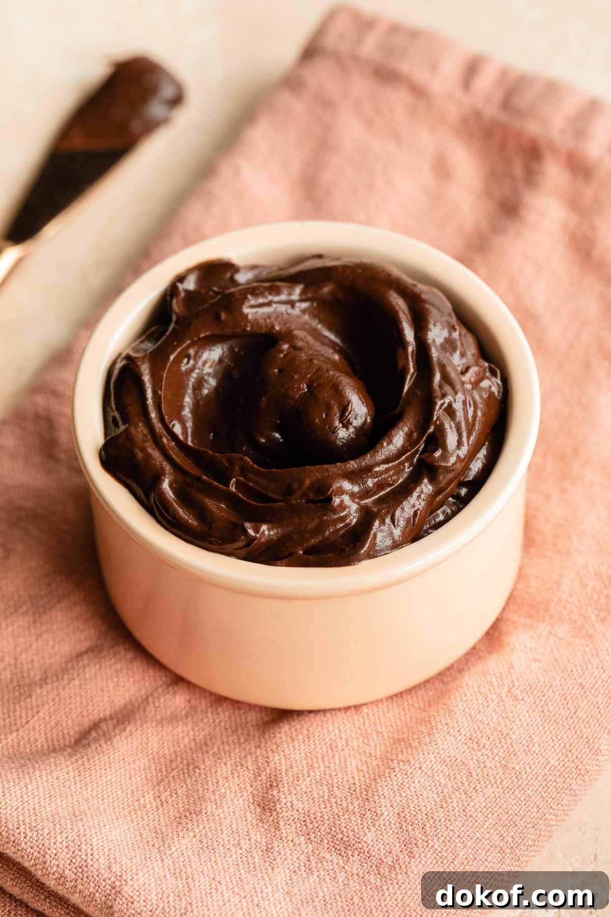 Avocado chocolate frosting in a pink dish on a pink napkin.