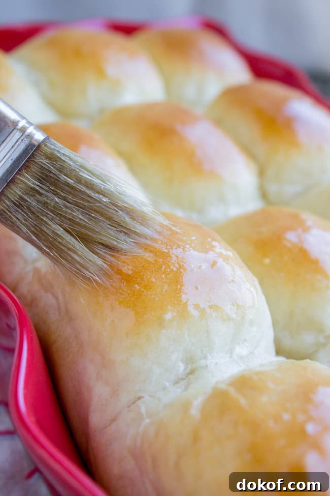 Brushing butter on homemade dinner rolls.