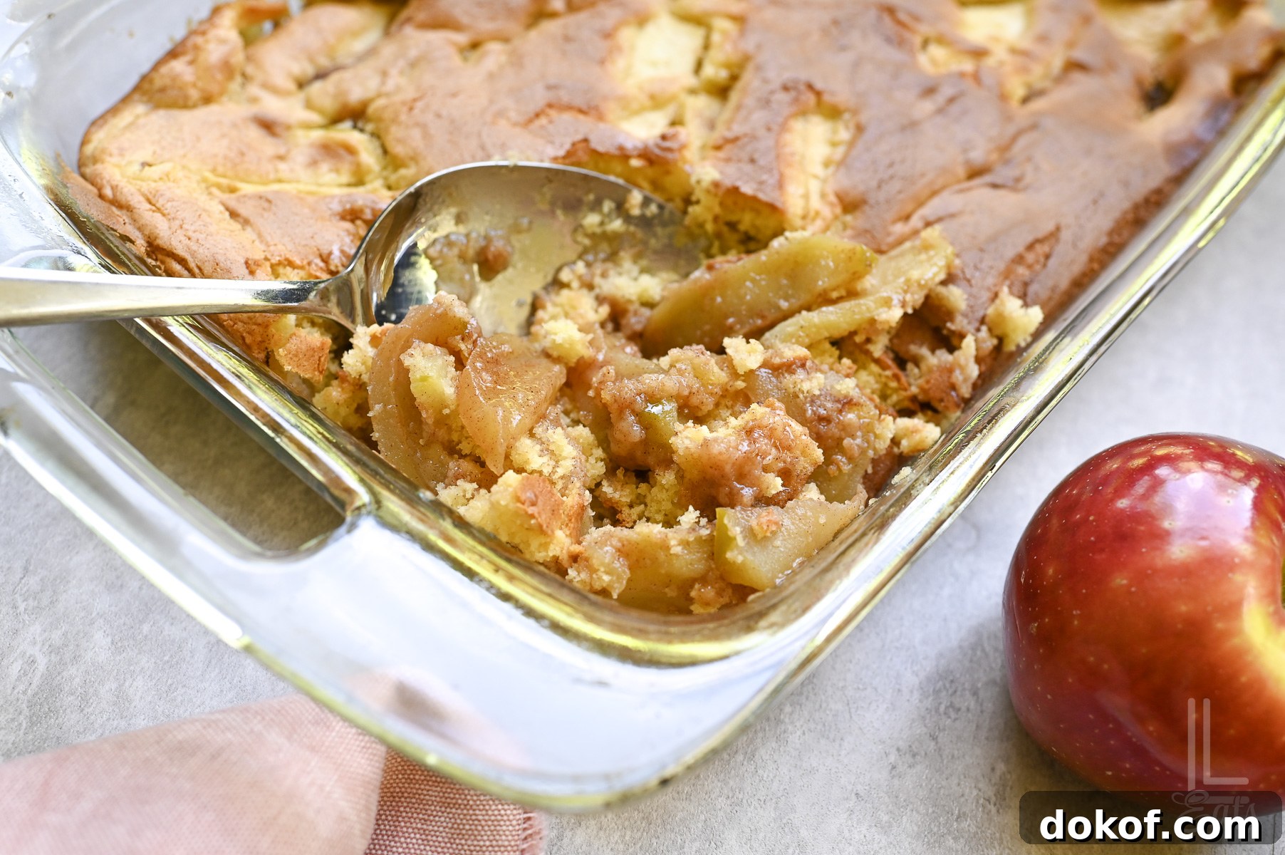spoon in a baking dish of apple cobbler made with cake mix.