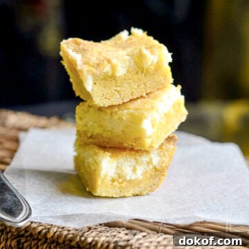 lemon chess bars stacked on parchment paper.
