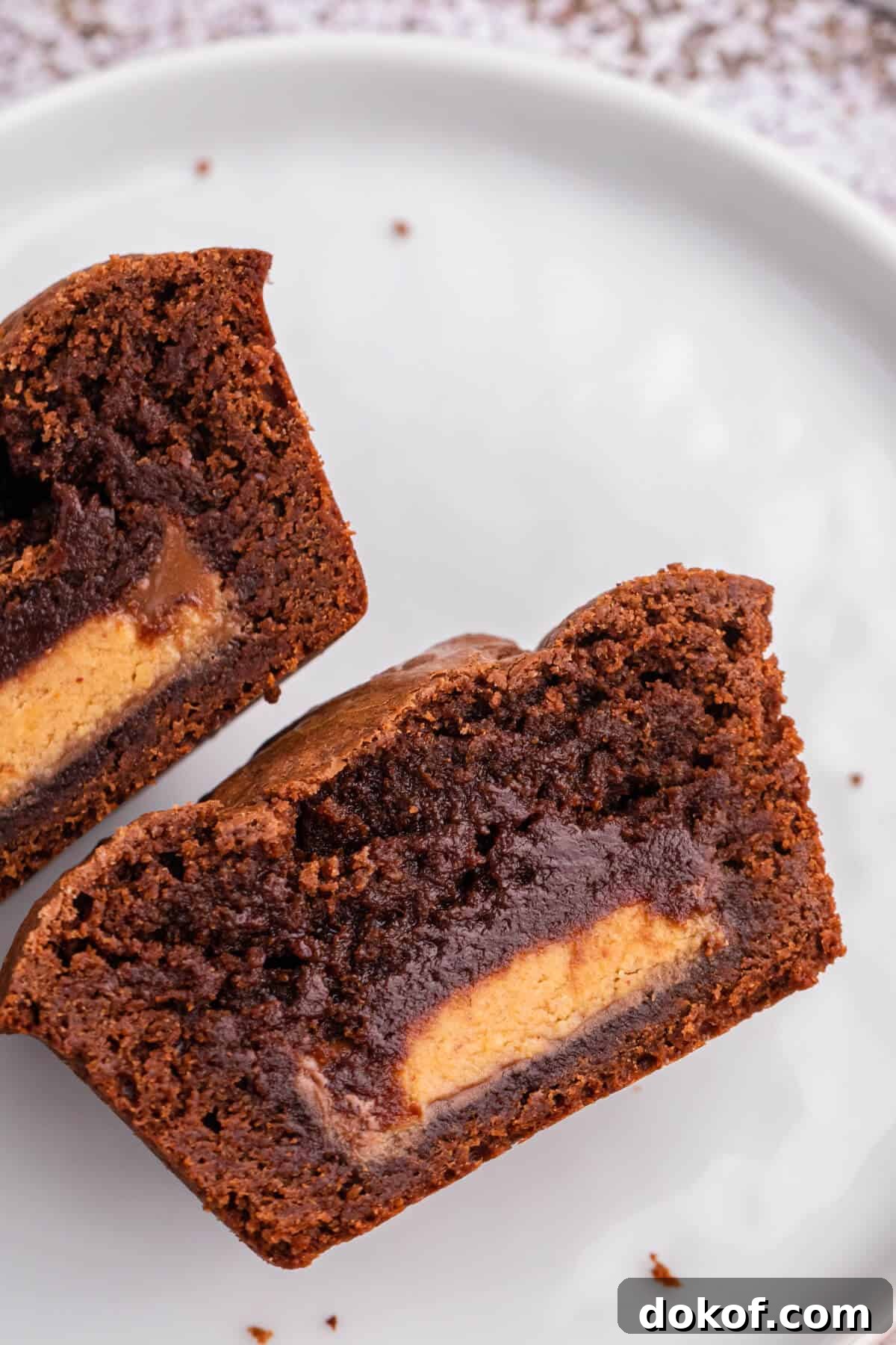 Reese’s Stuffed Brownies Recipe: Gooey Chocolate Peanut Butter Squares 5 Reese's stuffed brownies cut in half on a plate.