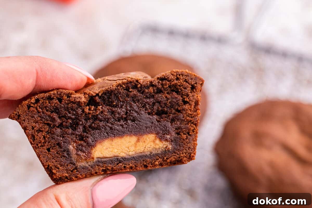 Reese’s Stuffed Brownies Recipe: Gooey Chocolate Peanut Butter Squares 6 A hand holding a Reese's stuffed brownies cut in half.