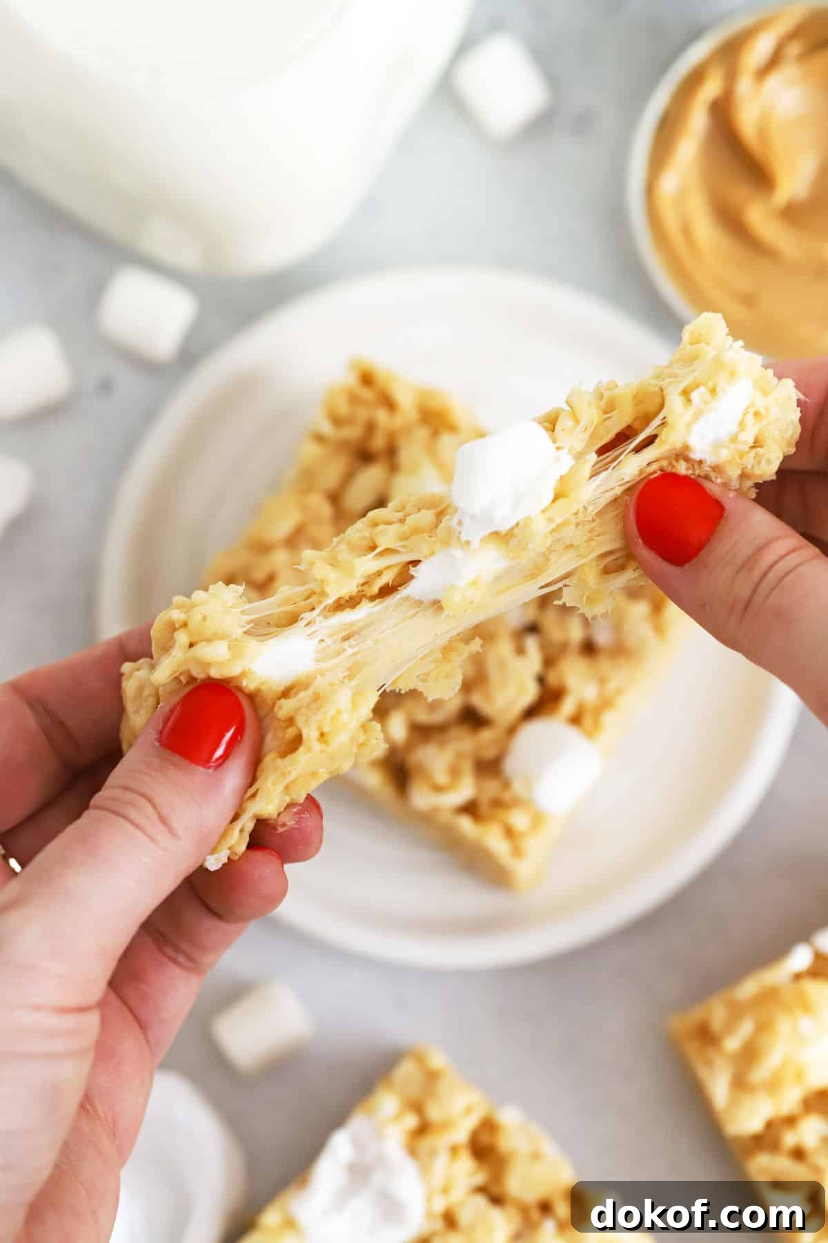 pulling a peanut butter rice krispie treat apart to show the gooey marshmallow