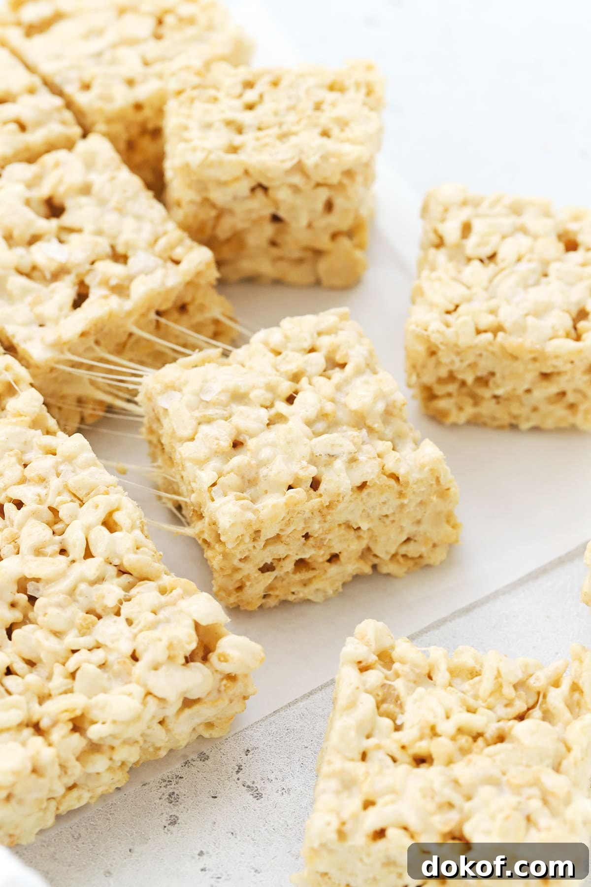 Pulling a square of gluten-free brown butter rice krispies treats away showing the gooey texture