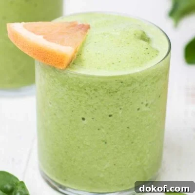 A close up look at a green smoothie garnished with a grapefruit slice.