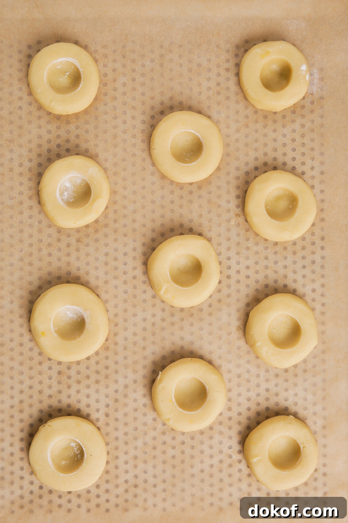 baking sheet with unbaked lemon thumbprint cookies