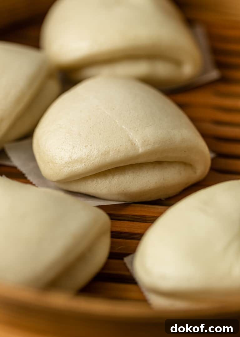 closeup: several bao buns in a wooden steamer, ready for pork buns