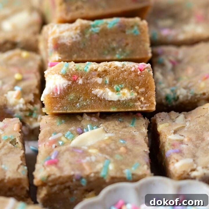 pile of birthday cake blondies showing the soft centers with sprinkles and white chocolate