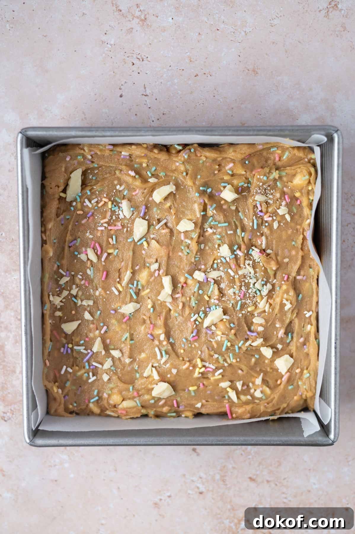 blondie batter with sprinkles and white chocolate in a baking pan