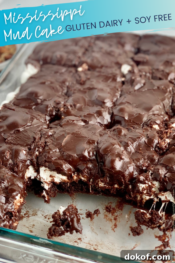 A glass baking dish filled with a dark brown chocolate cake followed by a white layer of mini marshmallows and topped with dark brown chocolate frosting. The bars have been cut into squares and some are missing from the pan.