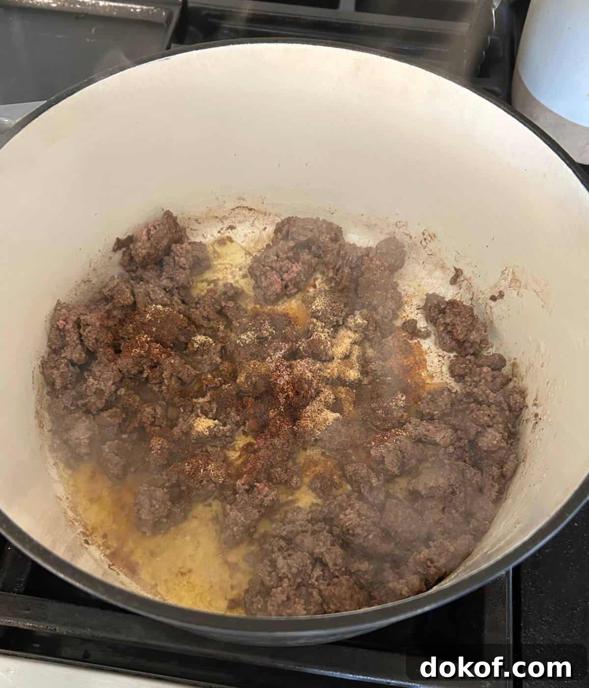 Ground beef cooking in dutch oven with seasonings.