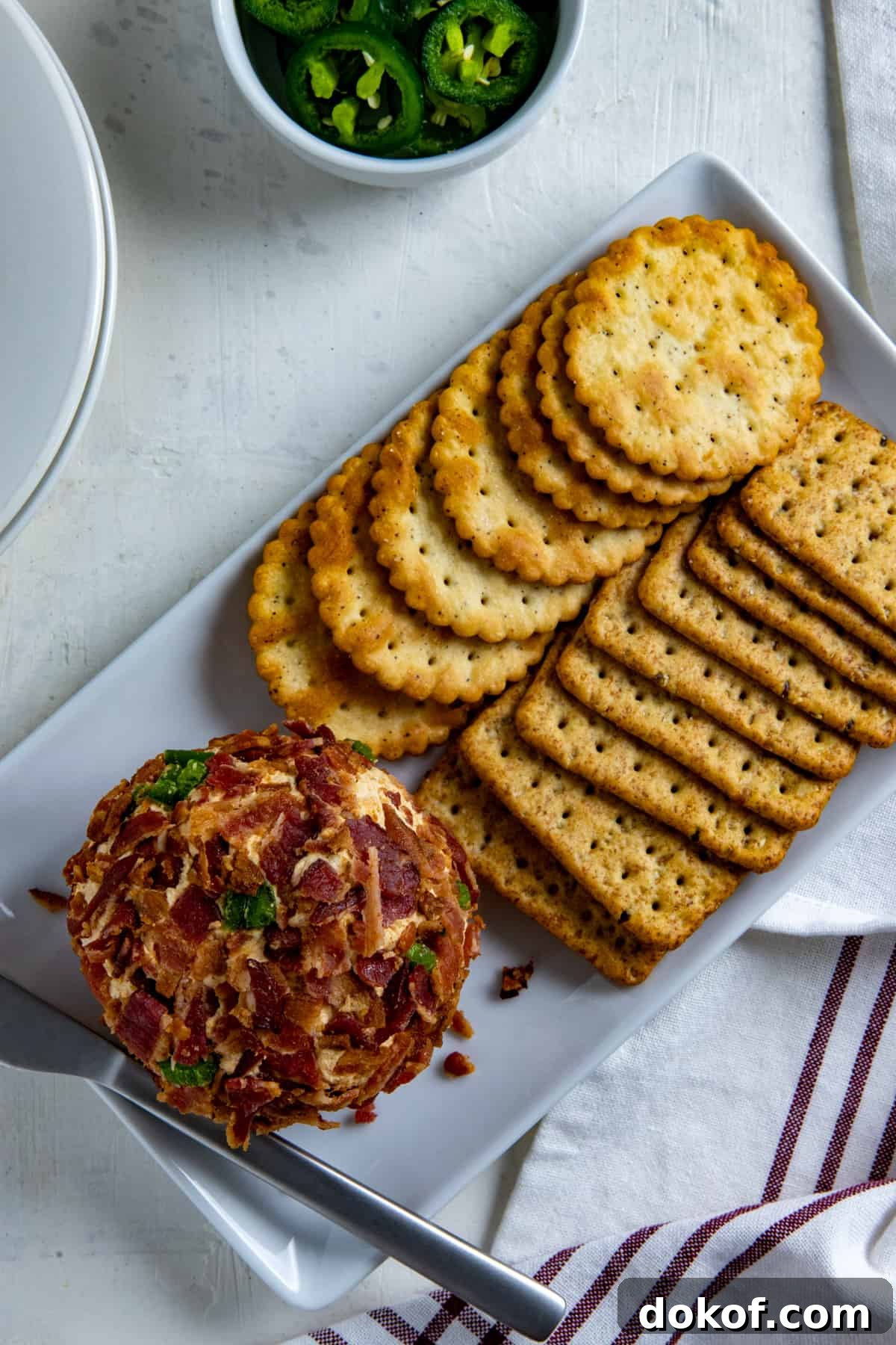 Jalapeno Cheese ball and Crackers on white rectangular serving dish.