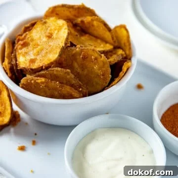 White bowl filled with fried potato slices plus a small bowl of ranch dressing on the side.