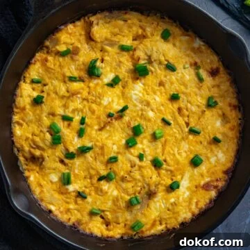 Baked dip topped with sliced green onions in a skillet.