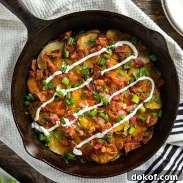 Layers of thin sliced potatoes with cheese and bacon in a cast iron skillet.