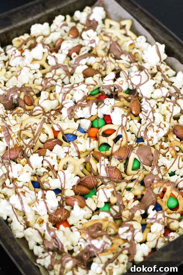 Savory Popcorn Trail Mix Recipe for Road Trips & Snacks 7 popcorn on a baking tray drizzled with chocolate..