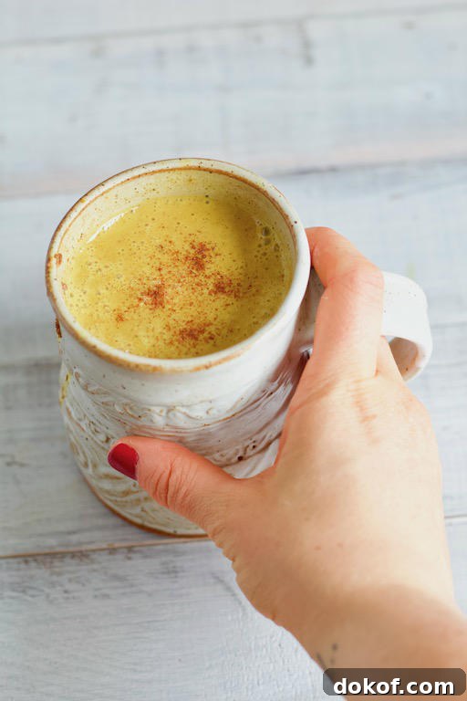 Hand Holding Mug of Pumpkin Spice Golden Milk Recipe