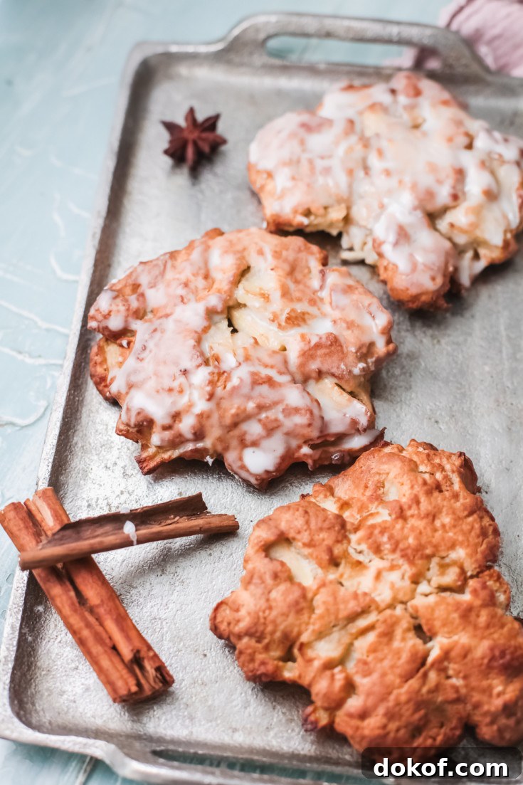 three completed apple fritters on a baking tray
