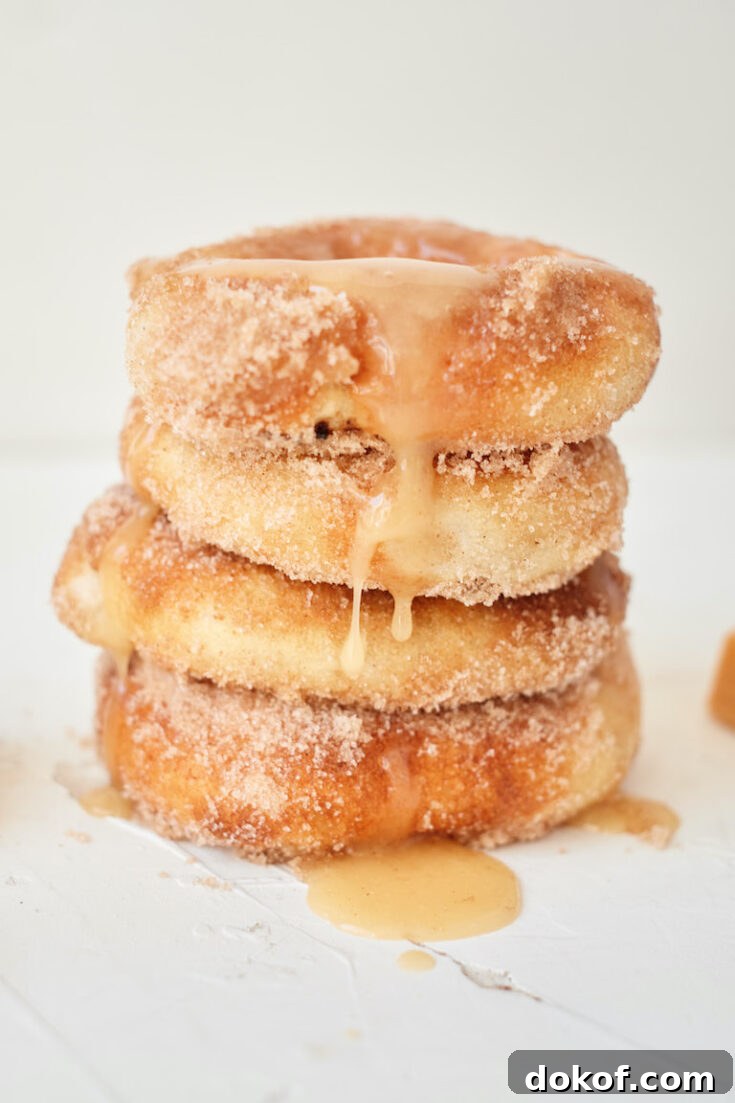 four air fryer caramel apple donuts stacked and drizzled with caramel sauce