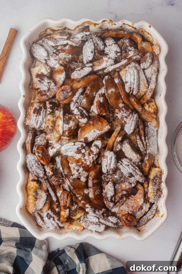 Baked apple French toast casserole dusted with powdered sugar and topped with pecans.