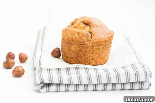 apple hazelnut muffins on a dish towel next to hazelnuts