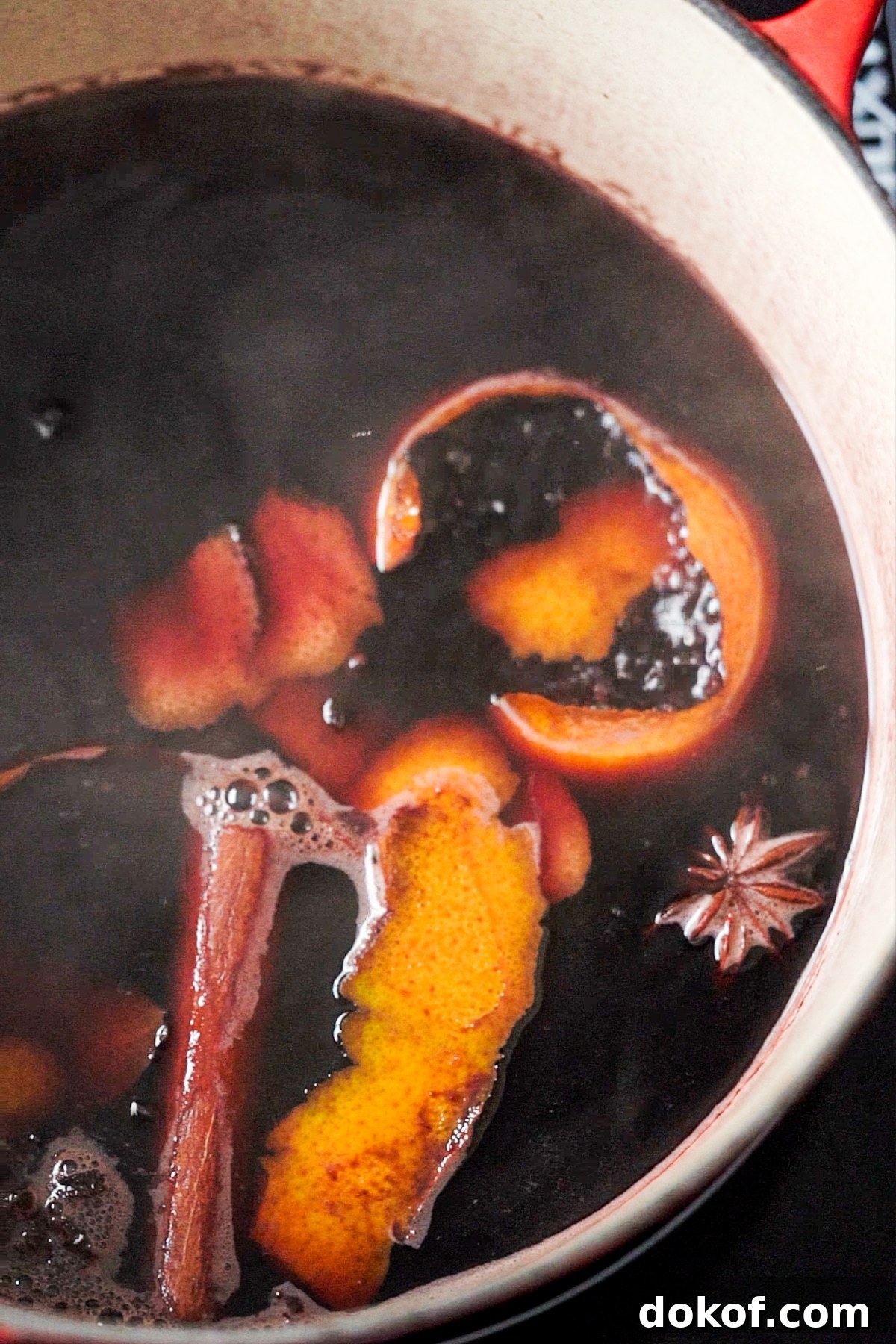 Simmering keto mulled wine in a dutch oven with cinnamon, star anise, orange, cloves and cinnamon