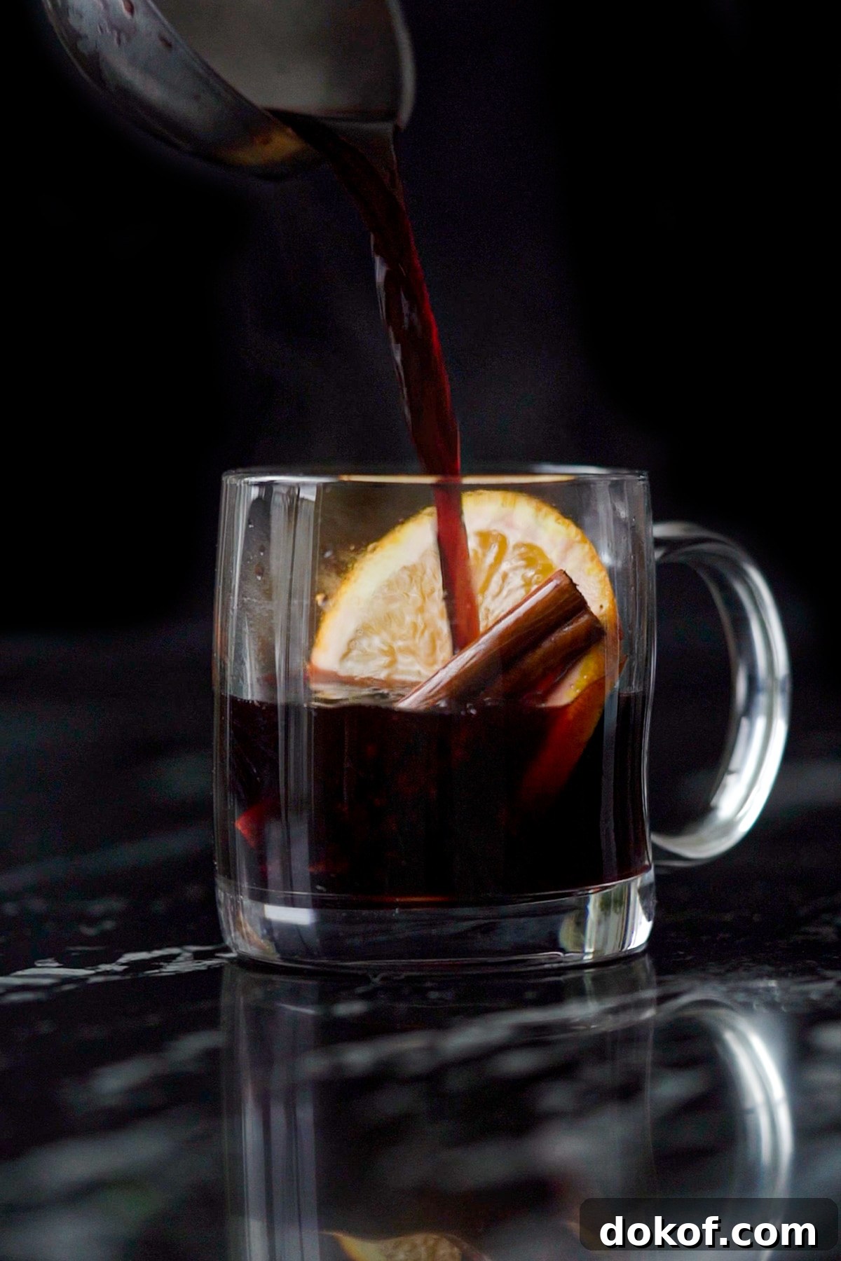 Pouring keto mulled wine onto a mug with an orange slice, cinnamon stick and star anise