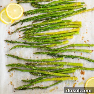 Crispy Oven-Roasted Asparagus with Garlic and Parmesan 5 Oven roasted asparagus and lemon slices on a baking sheet lined with parchment paper.