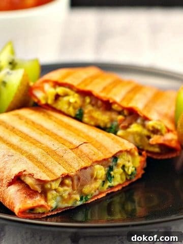 breakfast burrito on a black plate,. cut in half