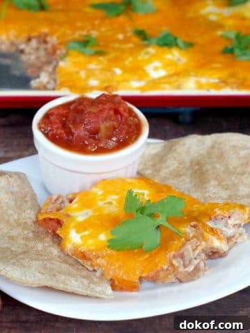 sheet pan huevos rancheros on a white plate with tortilla and salsa and sheet pan in background