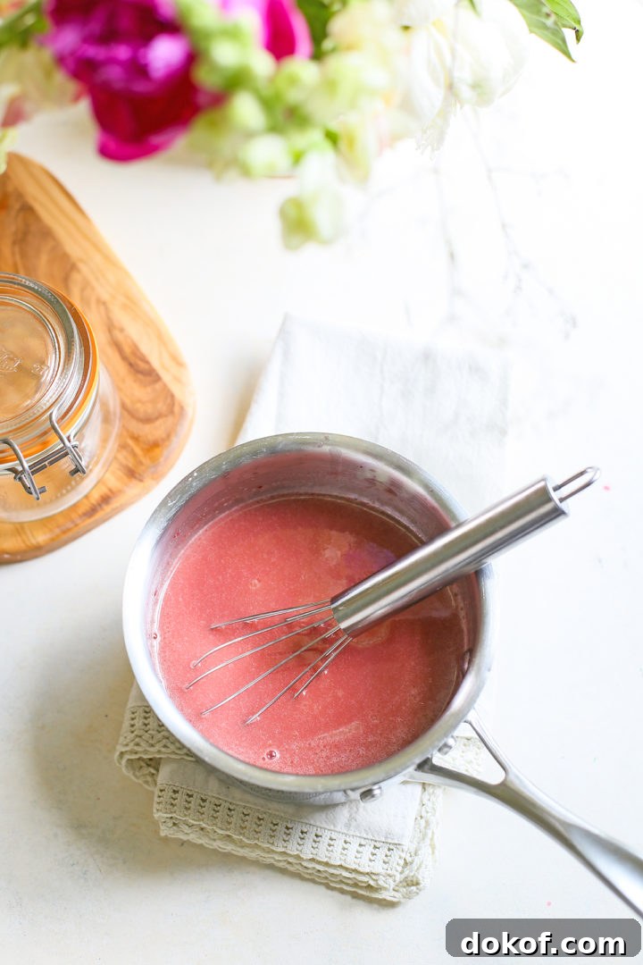 saucepan of prepared raspberry curd with a whisk in it