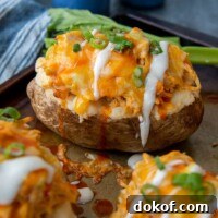 a buffalo chicken baked potato with ranch dressing drizzled over top