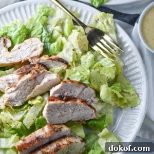 Caesar salad next to a cup of caesar salad dressing.