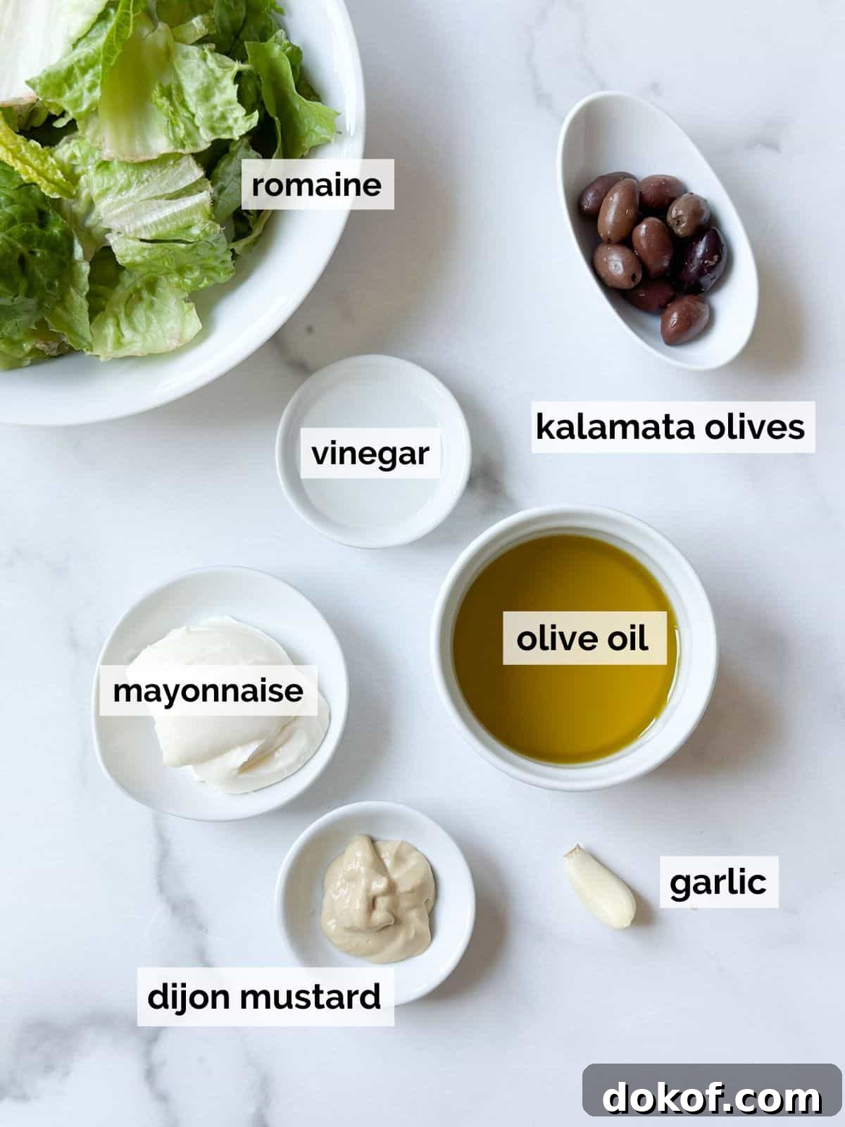 Ingredients for Caesar dressing on a white marble table.