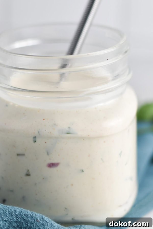 A jar of gluten free ranch dressing with a whisk.