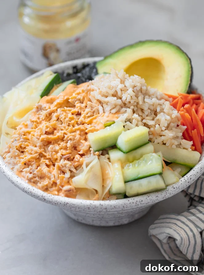 A tuna bowl with pickled cucumbers, carrots brown rice topped with spicy mayonnaise