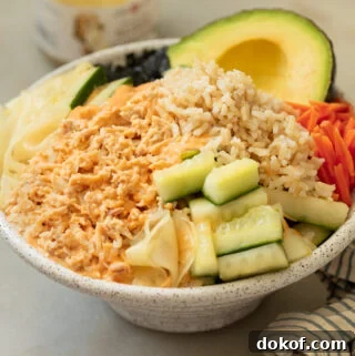A tuna bowl with pickled cucumbers, carrots brown rice topped with spicy mayonnaise