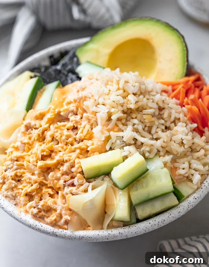 A tuna bowl with pickled cucumbers, carrots brown rice topped with spicy mayonnaise