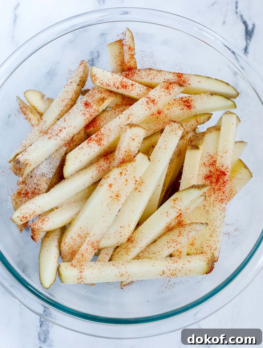 Seasoning hand cut french fries.