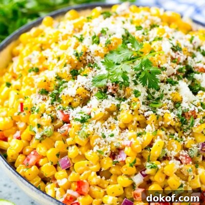 A bowl of Mexican corn salad topped with cheese and cilantro.